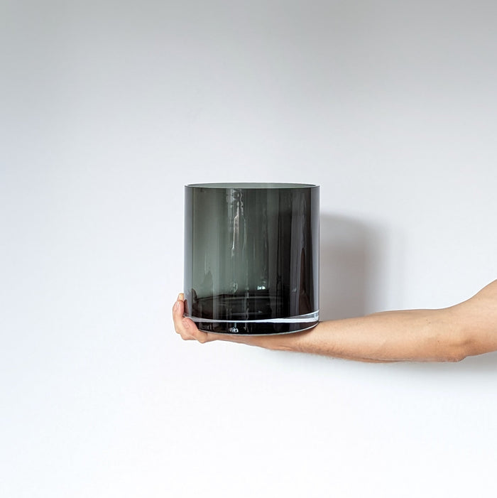 Moodbild schwarze Zylindervase aus Glas, welche in der Hand gehalten wird