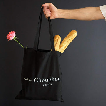 Moodbild mit schwarzem Tote Bag mit Schriftzug Mon Chouchou Zürich, in der Hand gehalten